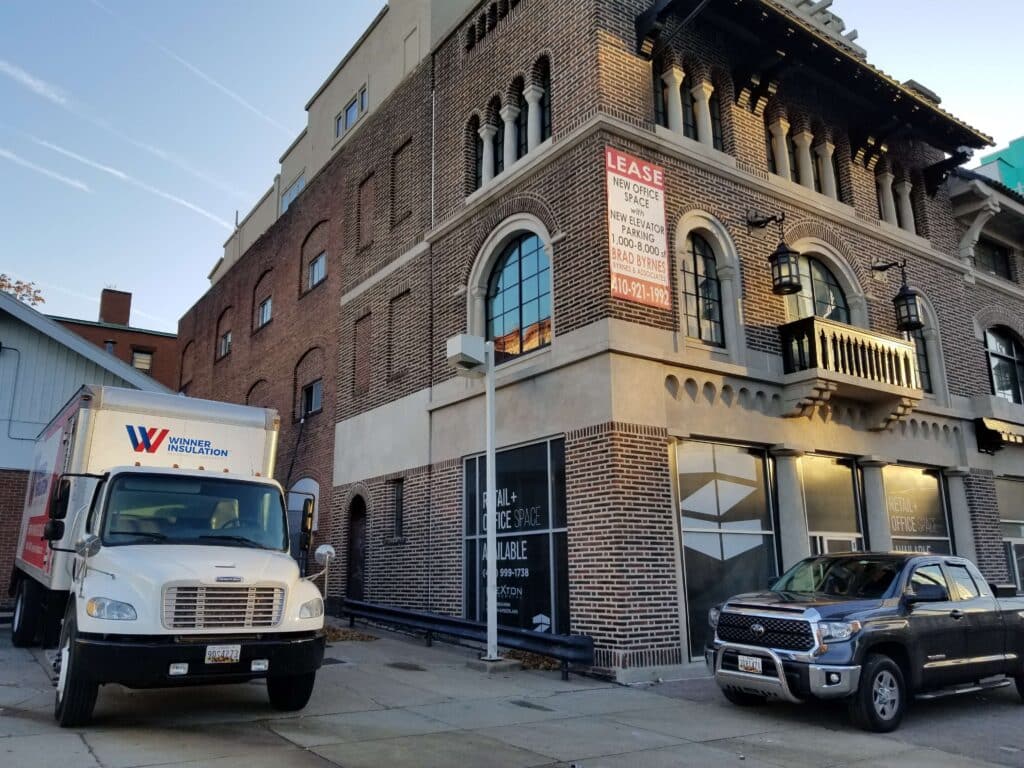 brick commercial building with Winner Insulation truck parked outside