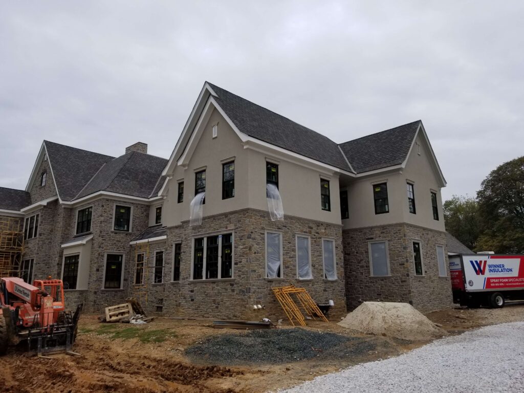 Large newly built home with stone facade on first floor and plastic on the windows.